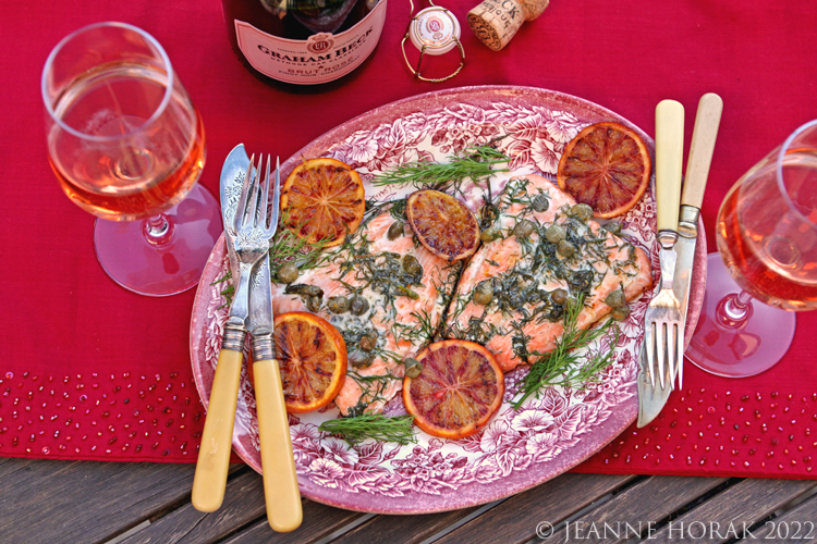 Barbecied salmon with blood oranges and capers on a red tablecloth