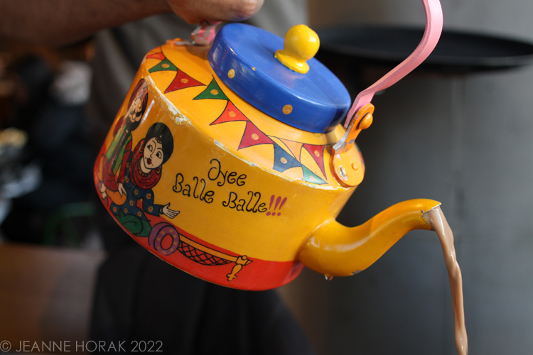 Chai being poured from a painted tea kettle